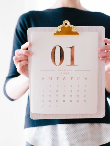 A woman holds up a calendar on January 1st.